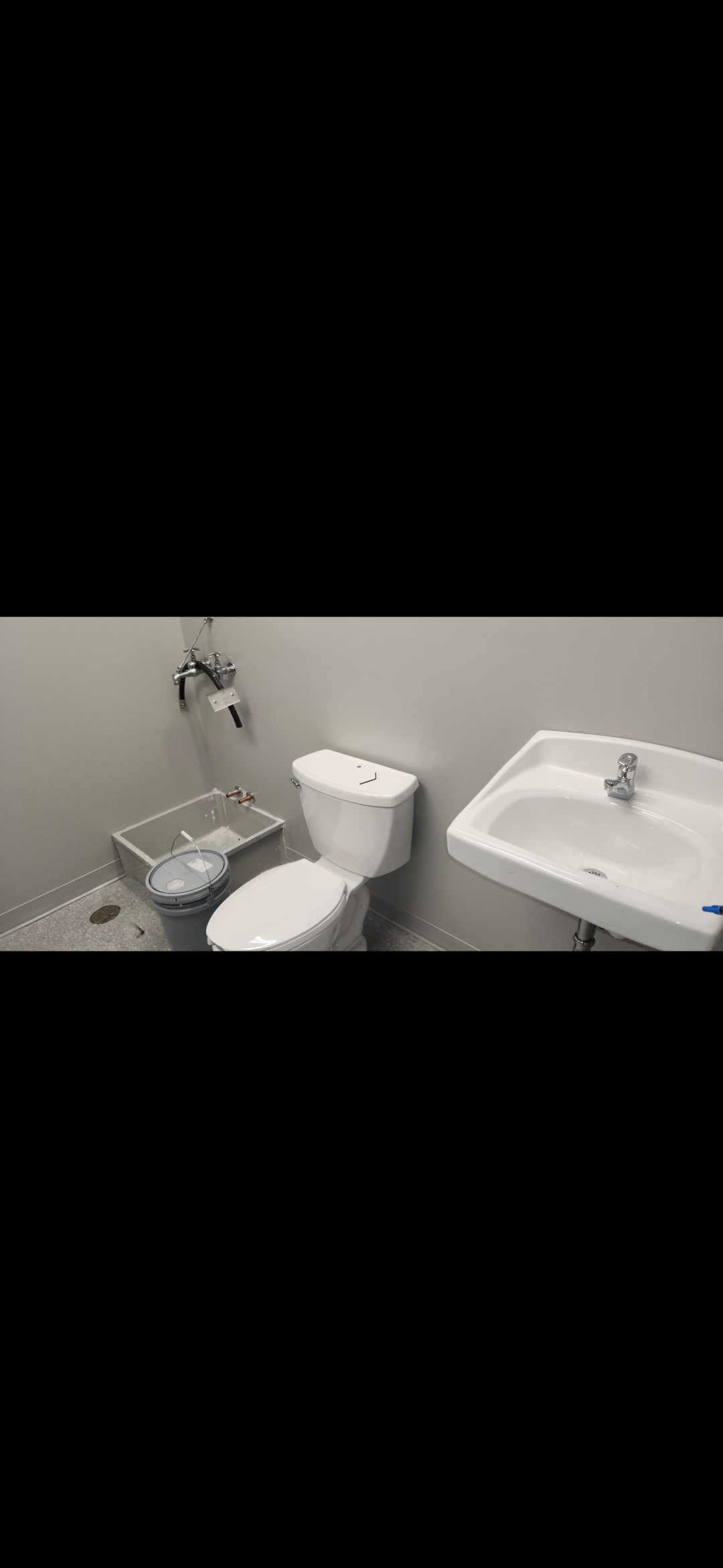 Commercial bathroom with sink and toilet — plumbing complete